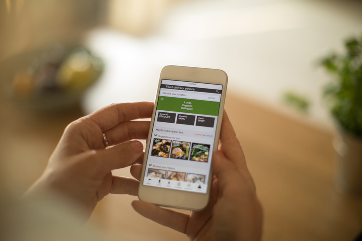 Woman using meal delivery service through mobile app.